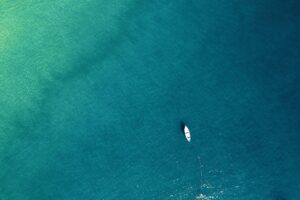 solitary boat on blue water seen from above