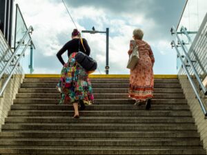 Two women of different ages walking up concrete stairs outdoors