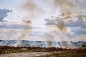 Field fire with smoke rising into the sky on open land