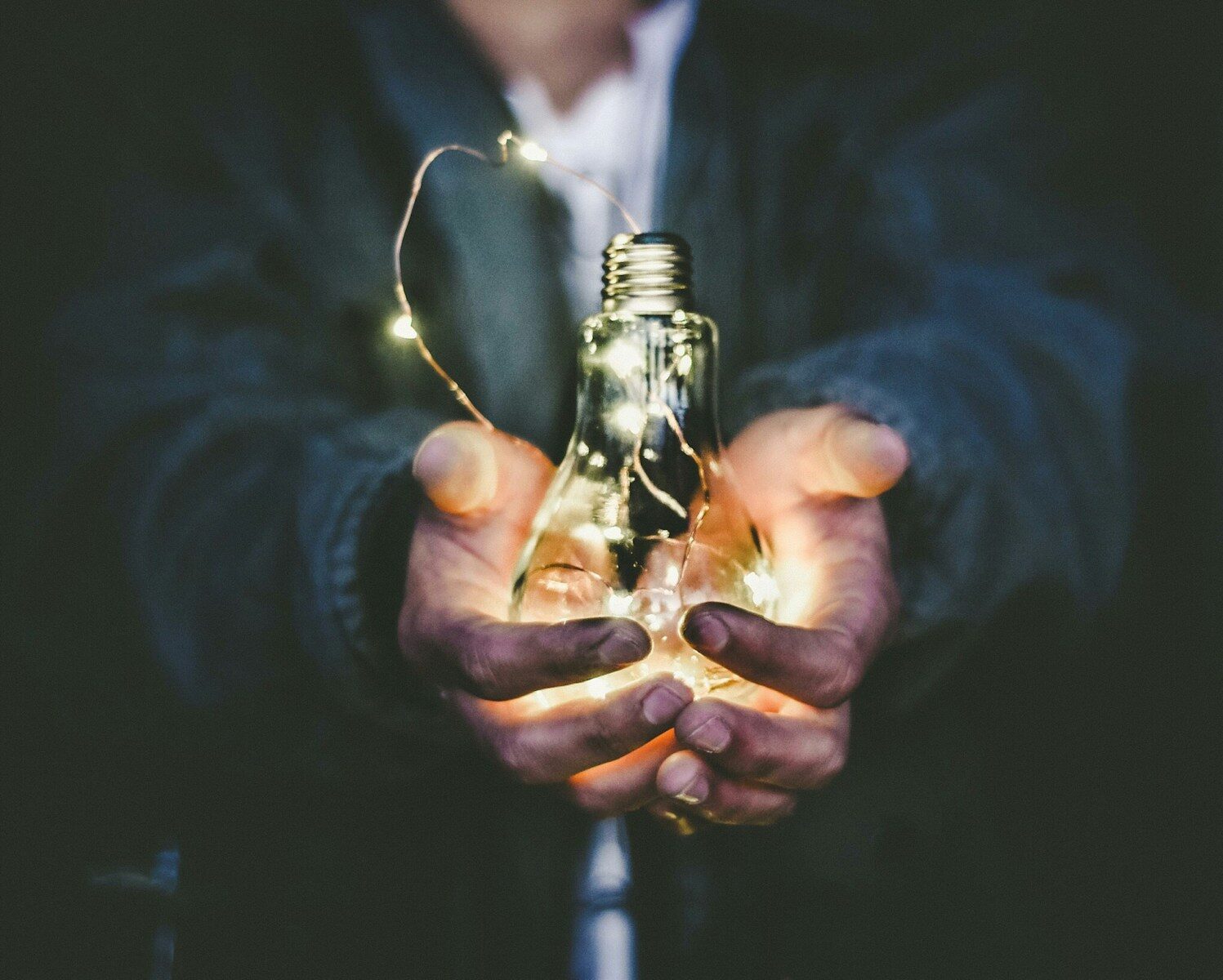 A person presents a glowing lightbulb symbolizing inspiration and new ideas