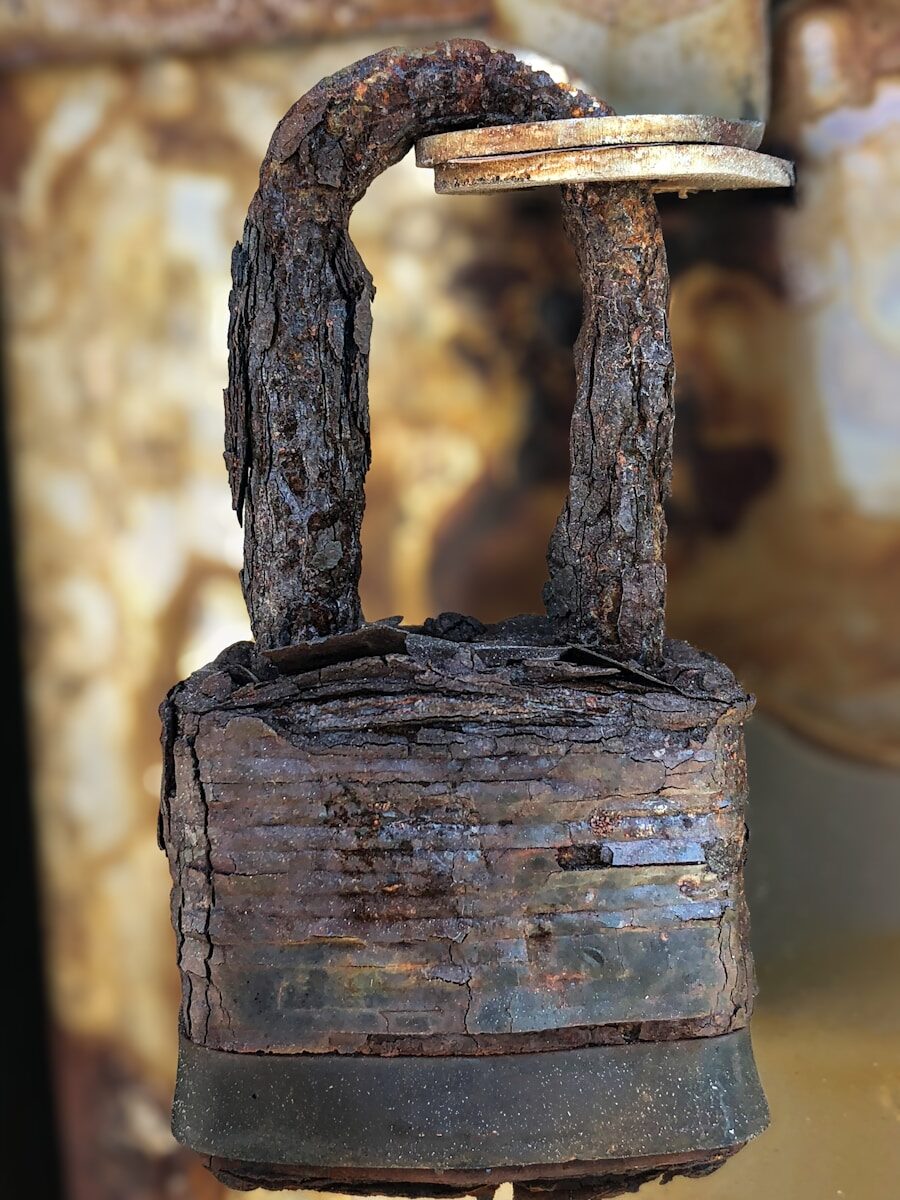 A close-up image of a padlock almost completely corroded by rust.