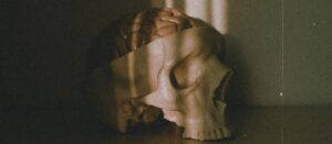 A skull with a brain cast in dramatic sunlight shadows on a floor, creating a moody atmosphere.