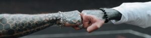 Two tattooed arms fist bump outdoors, symbolizing friendship or solidarity.